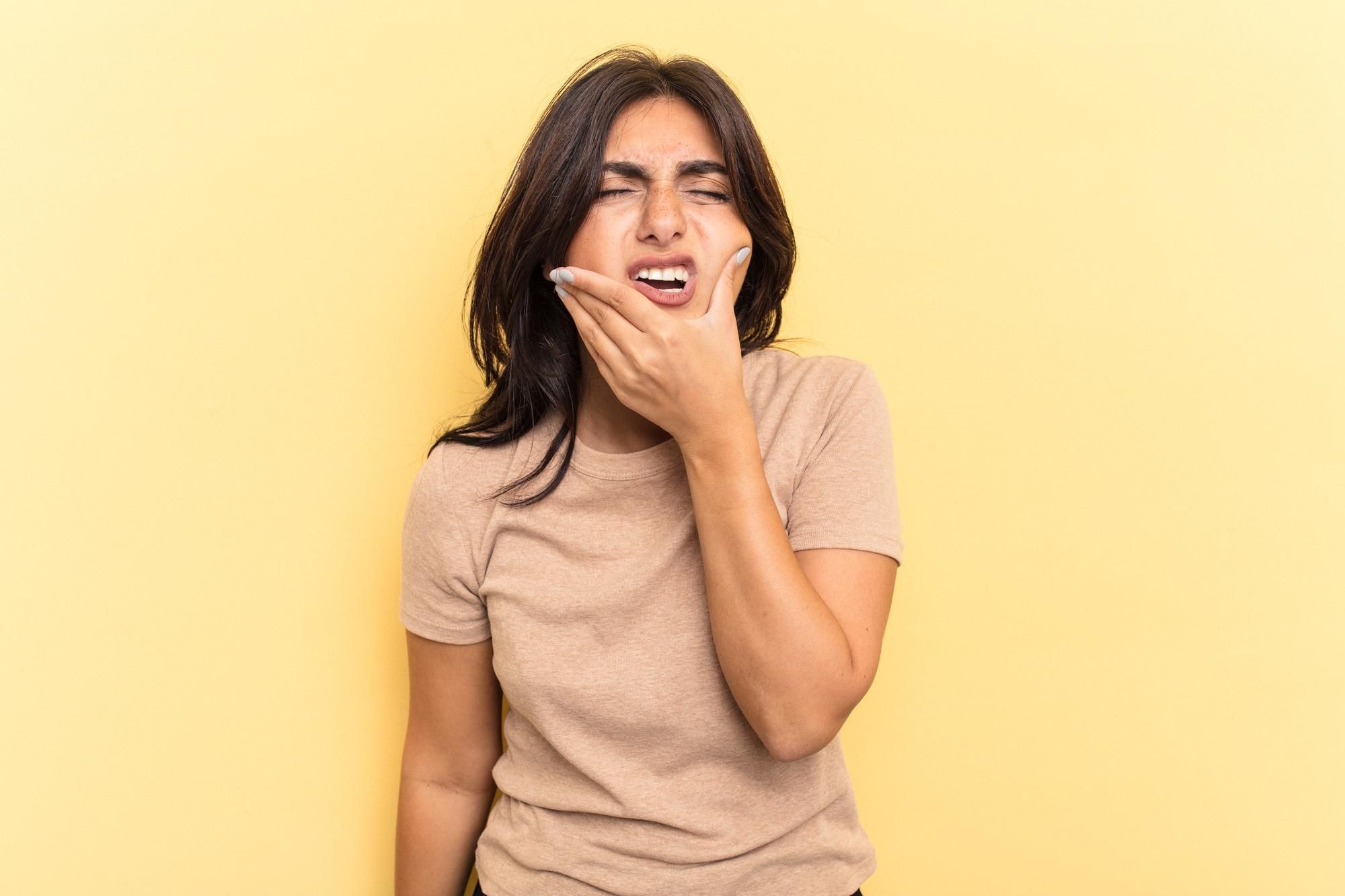 Una mujer con cara de dolor tras morderse la lengua.