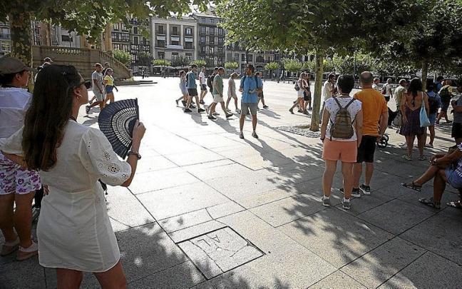 Un grupo de turistas escucha a la sombra las explicaciones de su guía ayer en la Plaza del Castillo, mientras otros visitantes cruzan por detrás. Un grupo de turistas escucha a la sombra las explicaciones de su guía ayer en la Plaza del Castillo, mientras otros visitantes cruzan por detrás.