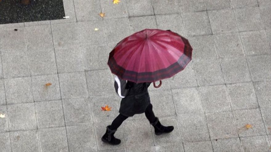 Una persona se cobija bajo un paraguas ante la tormenta.