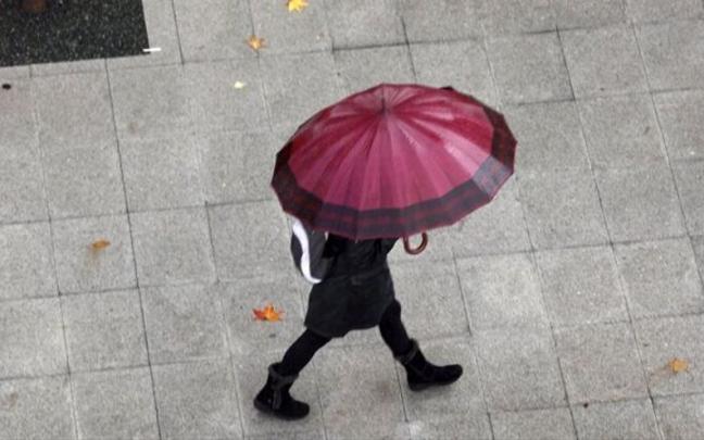 Una persona se cobija bajo un paraguas ante la tormenta.