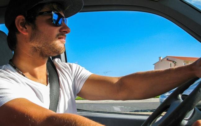Un hombre joven conduce su coche en verano. Un hombre joven conduce su coche en verano.