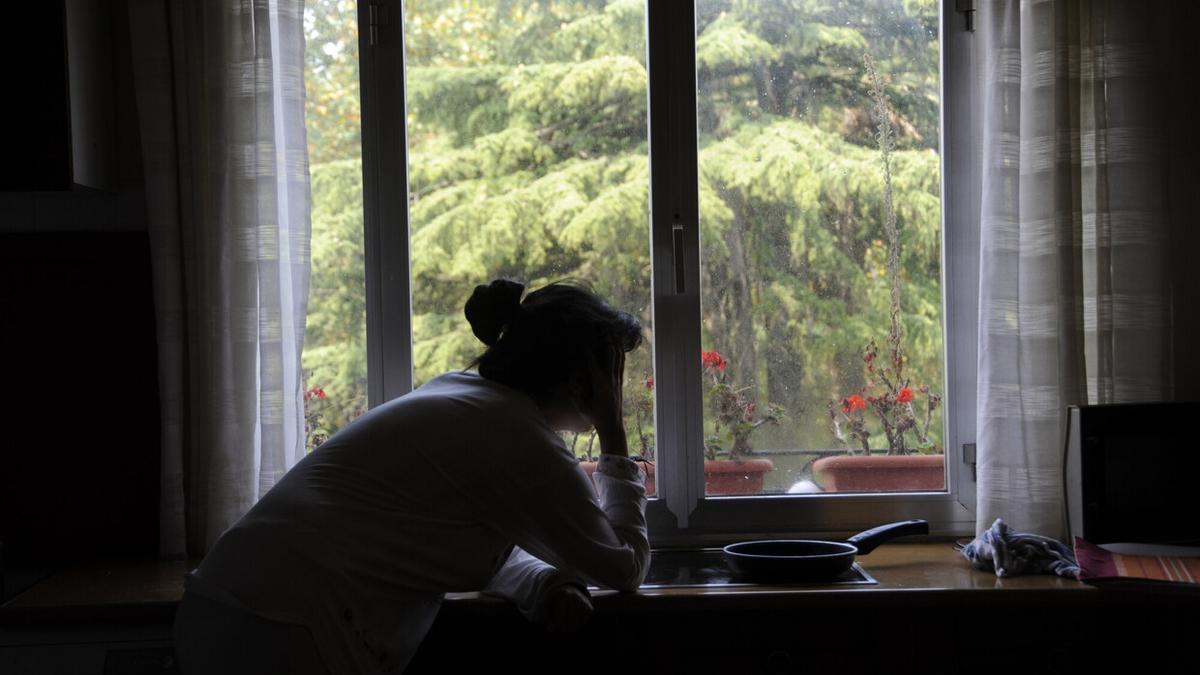 Imagen de archivo de una mujer mirando por la ventana.