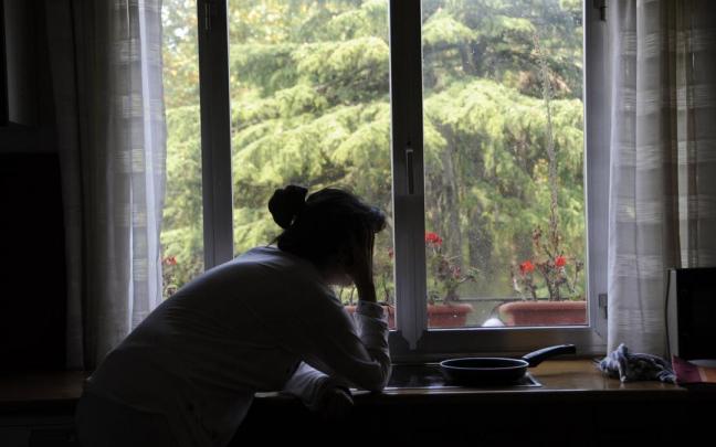 Imagen de archivo de una mujer mirando por la ventana.