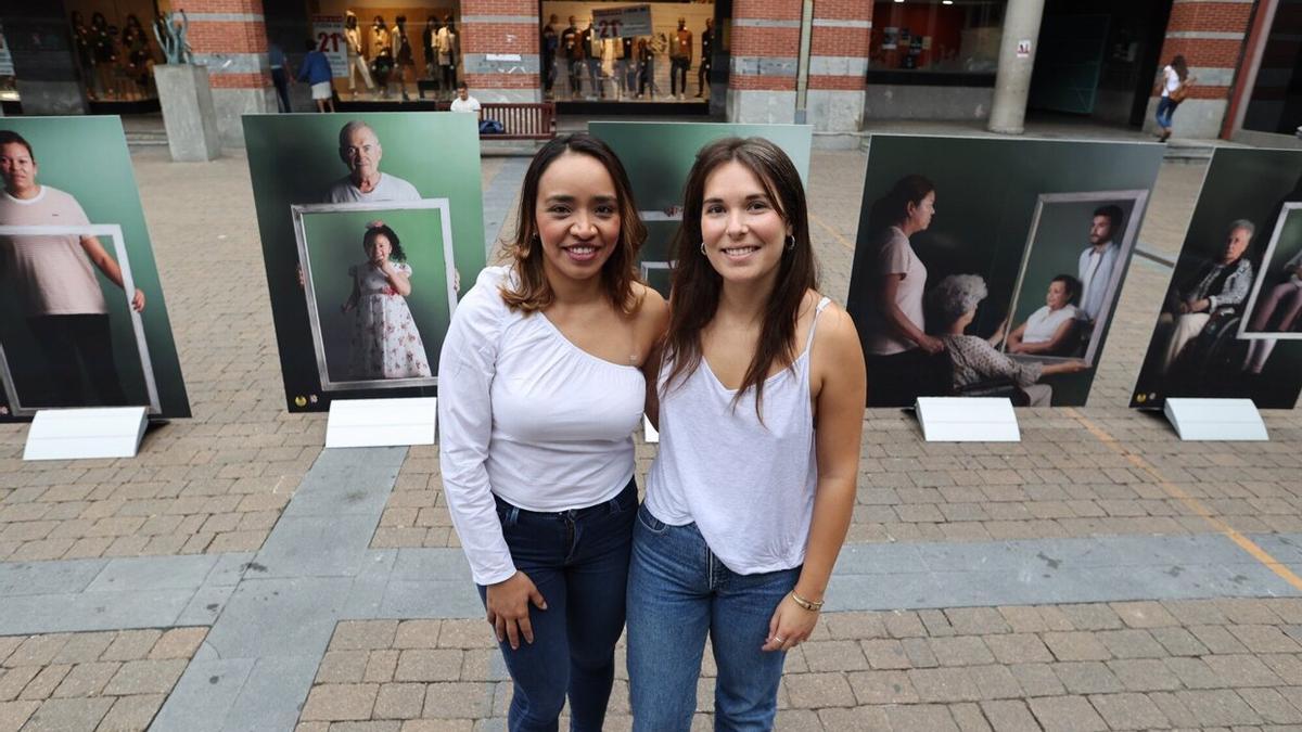 Tatiana Bellorin y Jone Urionaguena, integrantes de SOS Racismo Gipuzkoa, junto a la exposición fotográfica de Errenteria que interpela a la ciudadanía para generar espacios de encuentro entre trabajadoras del hogar y familias emplead