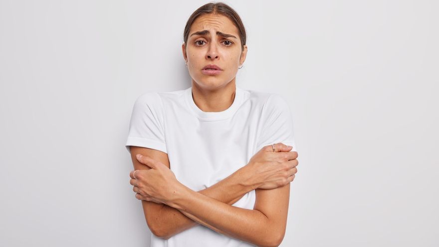 Una mujer con camiseta de manga corta y con cara de frío.
