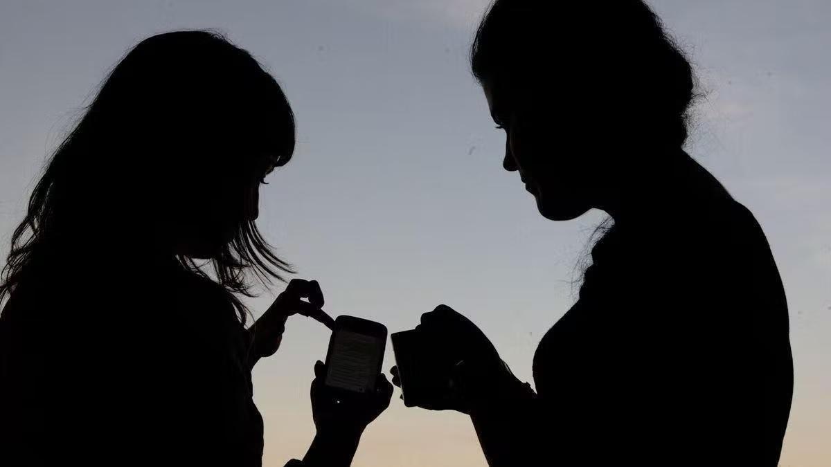 Dos jóvenes consultan un teléfono móvil