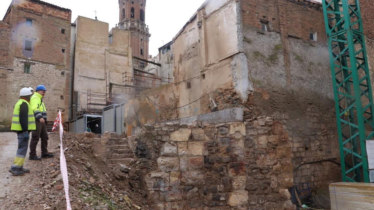 Los arqueólogos observan el muro islámico, en primer término, y detrás las escaleras del sótano, al fondo la torre de la catedral.