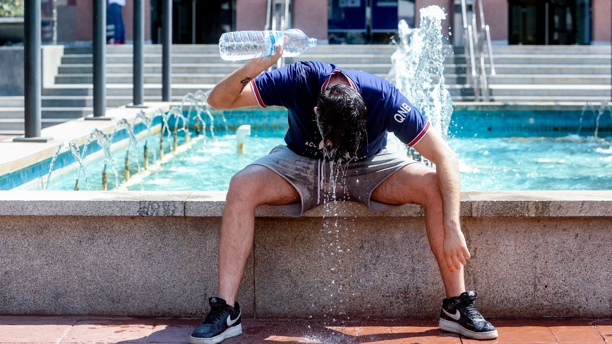 Un joven se refresca junto a una fuente durante la segunda ola de calor del verano.