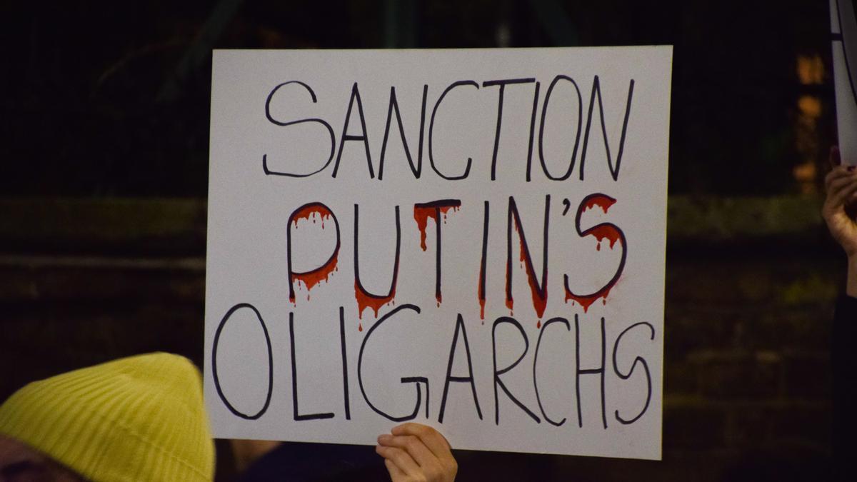 Un manifestante sostiene una pancarta "Sancionar a los oligarcas de Putin".