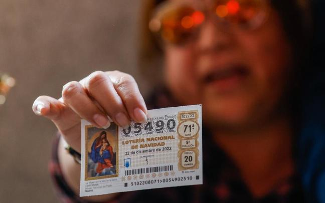 Una mujer sostiene un décimo del número premiado con el Gordo de 2022. Una mujer sostiene un décimo del número premiado con el Gordo de 2022.