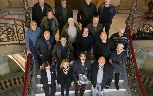 Integrantes del club Ur-Kirolak, representantes del Ayuntamiento de Donostia y el escritor posan en el interior del Consistorio.
