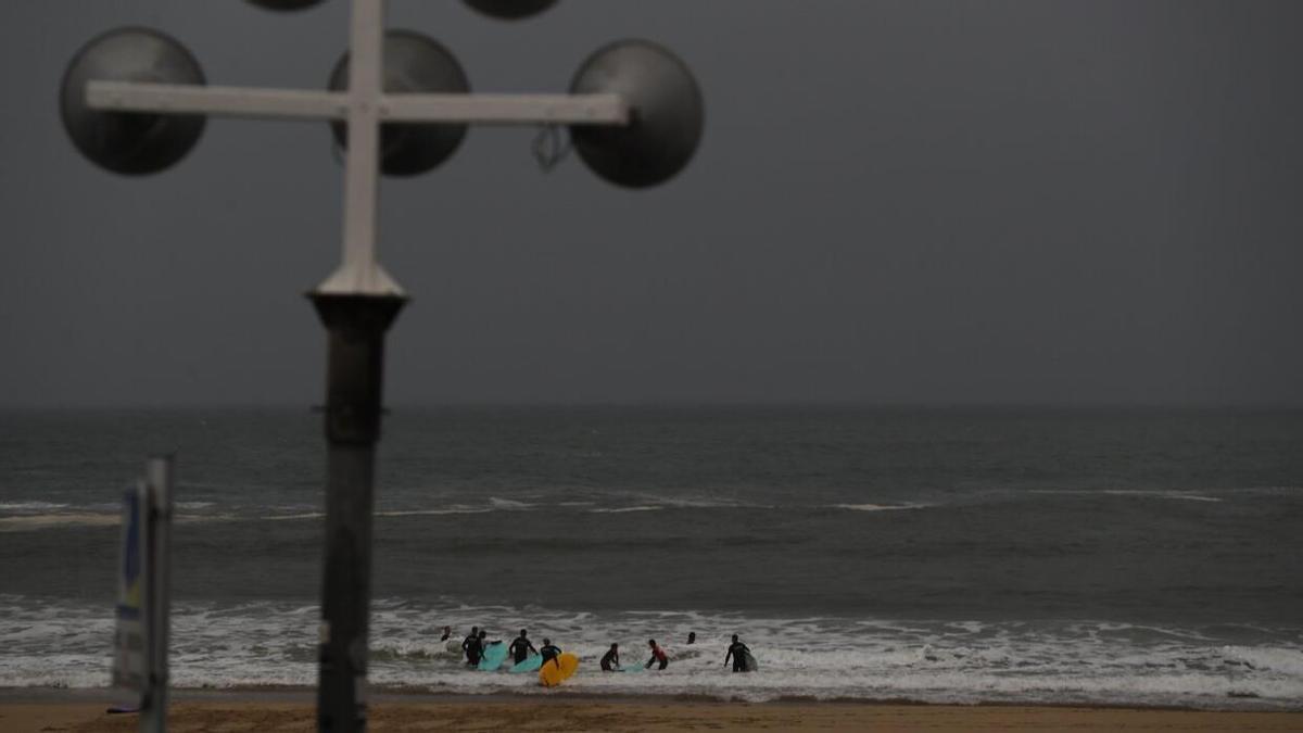 Unos deportistas practican surf en la playa de la Zurriola este jueves