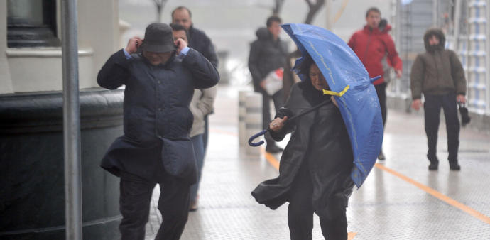 Dos personas tratan de protegerse del viento en Donostia