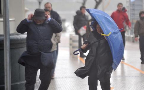 Dos personas tratan de protegerse del viento en Donostia