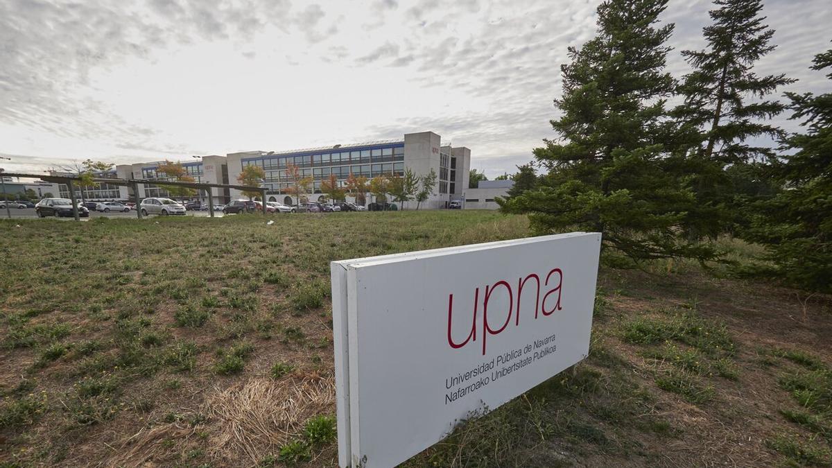 Letrero de la UPNA en el campus con edificios de la universidad pública al fondo