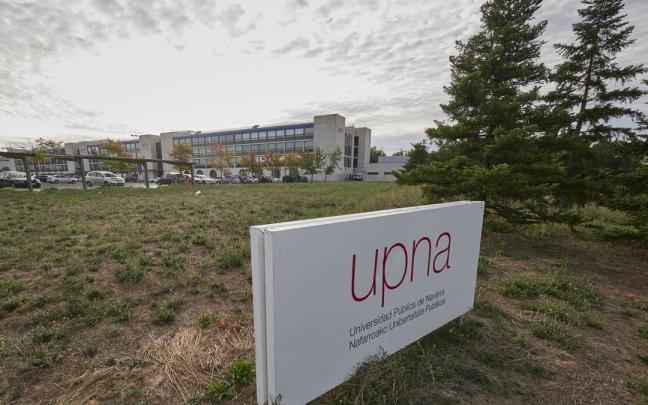 Letrero de la UPNA en el campus con edificios de la universidad p&uacute;blica al fondo