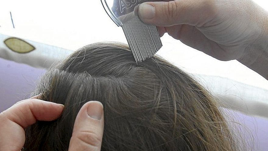 Una madre vigila el cabello de su hija.