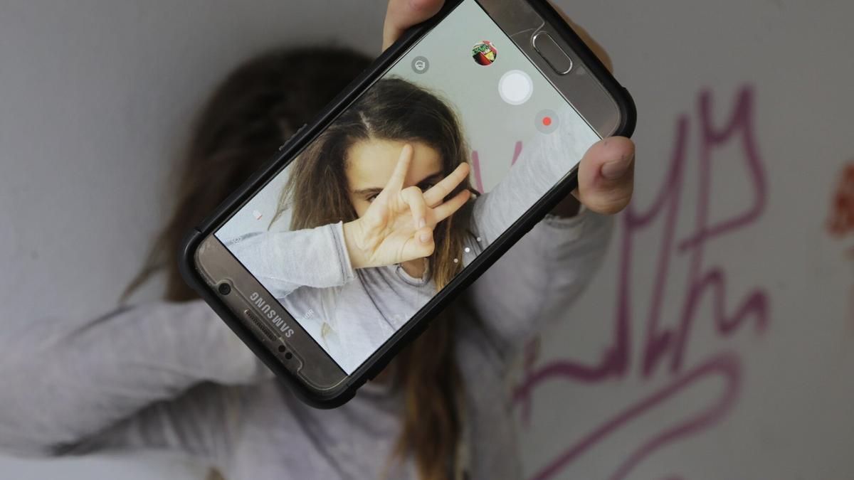 Una niña se hace un selfi con su teléfono móvil mientras los expertos piden que se racione la cantidad y los momentos del uso del mismo.