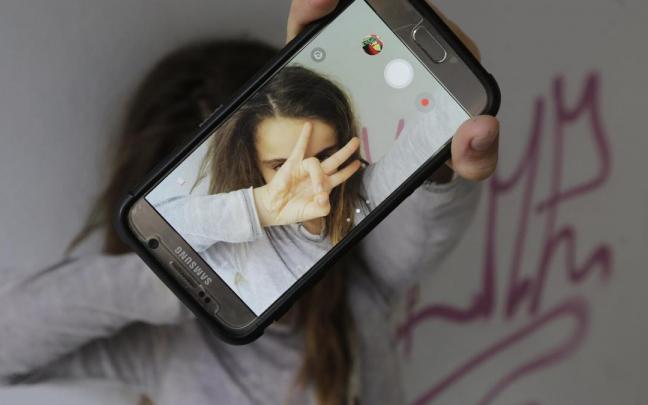 Una niña se hace un selfi con su teléfono móvil mientras los expertos piden que se racione la cantidad y los momentos del uso del mismo. Una niña se hace un selfi con su teléfono móvil mientras los expertos piden que se racione la cantidad y los momentos del uso del mismo.