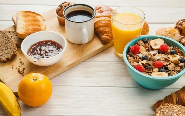 Caf&eacute;, boller&iacute;a, fruta, pan y cereales listos para ser degustados en el desayuno.