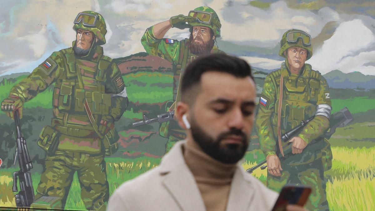 Un hombre observa su teléfono en Moscú ante un mural de las tropas rusas.