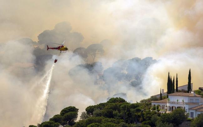 Un helic&oacute;ptero trata de sofocar un incendio forestal en Catalunya.