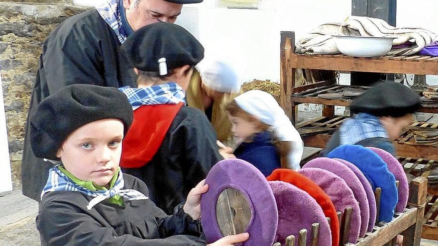 Un niño observa txapelas de diferentes colores.