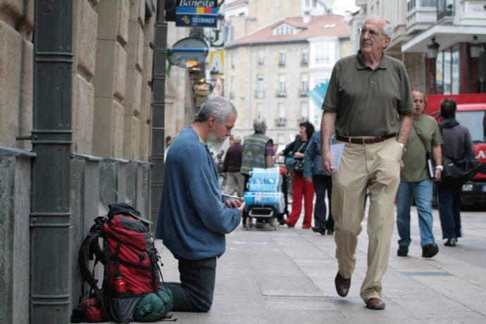 Una persona pide dinero en una calle céntrica de la ciudad.