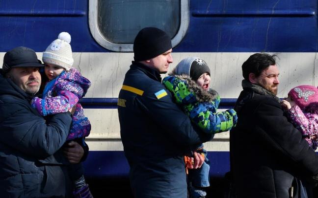 Ni&ntilde;os ucranianos con sus padres antes de subirse a un tren.
