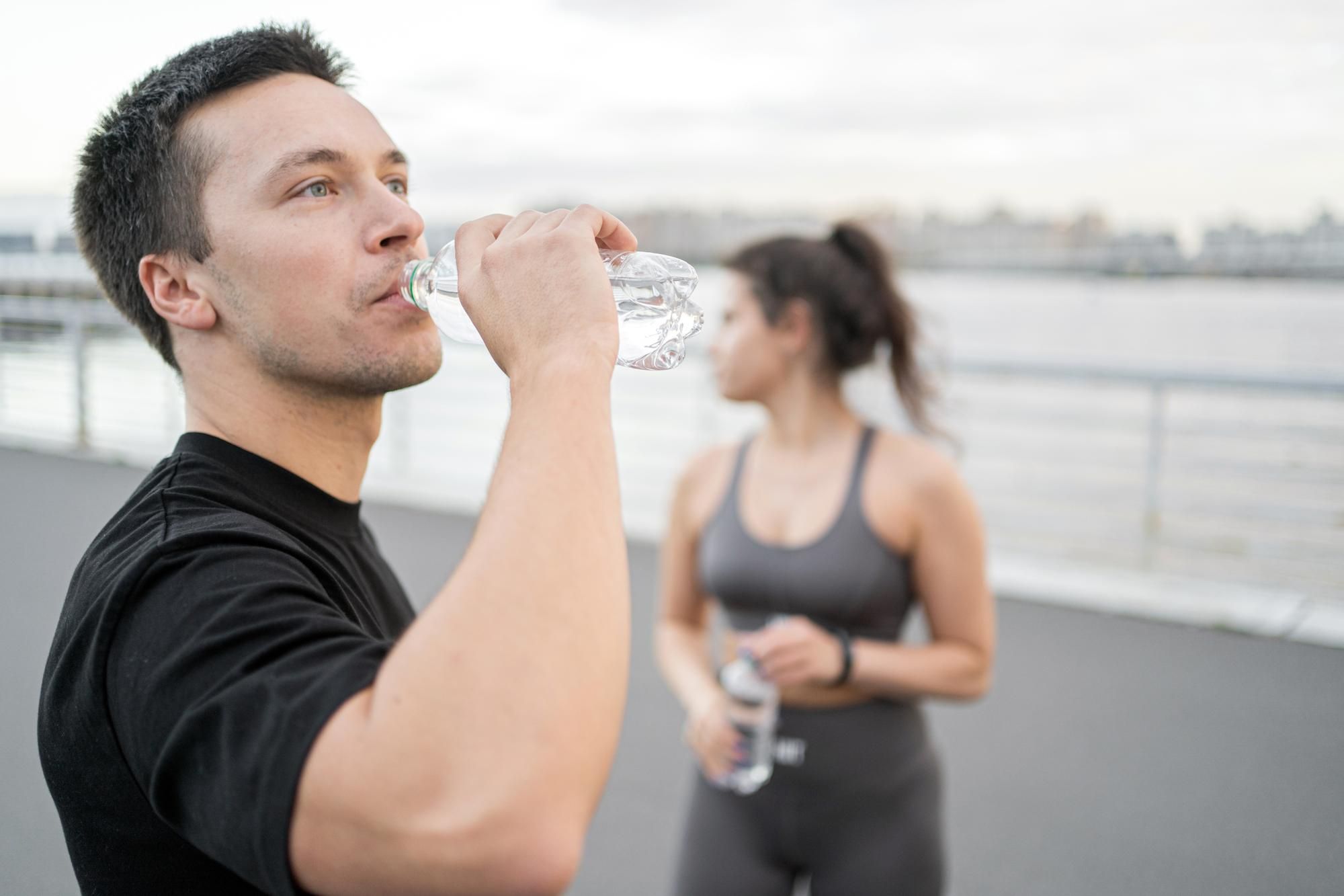 Un hombre bebe agua mientras practica deporte.