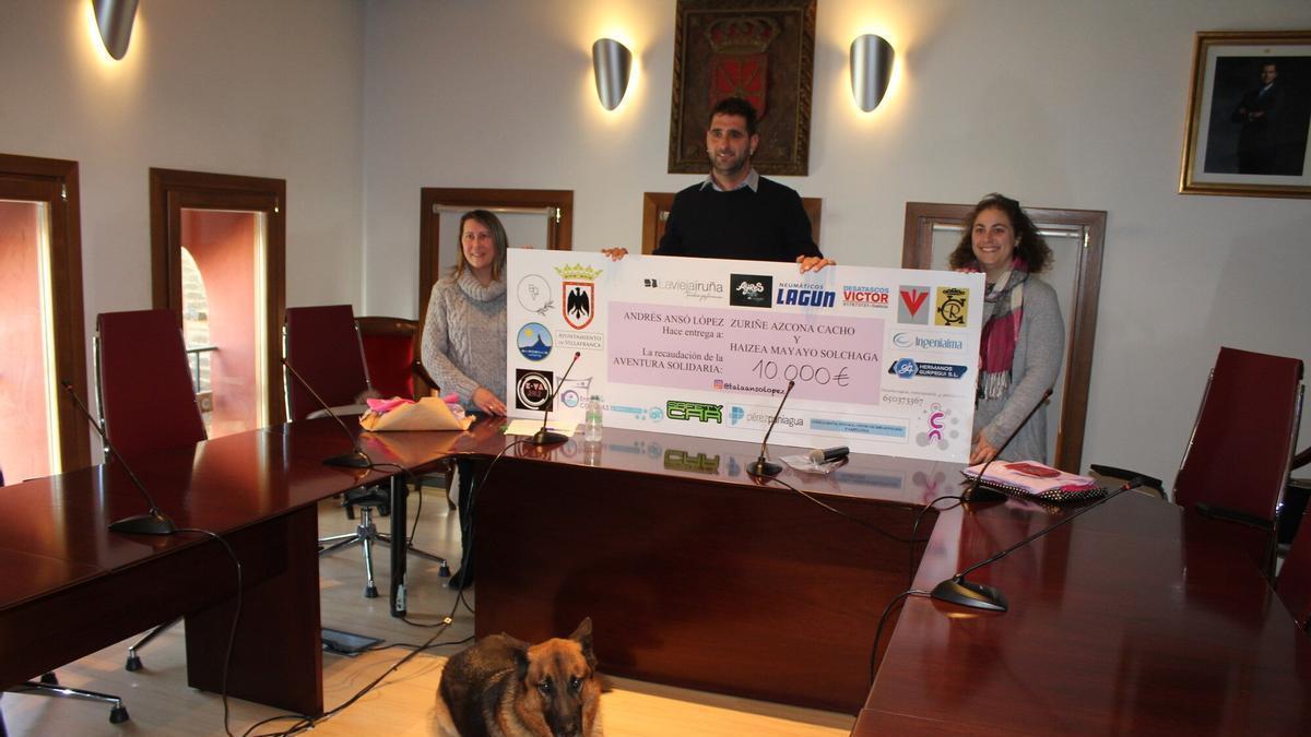 Andrés Ansó, en el centro, sujeta el cheque del donativo de 10.000 euros junto a la madre de Haizea y la tía de Zuriñe, en el Ayuntamiento de Villafranca.