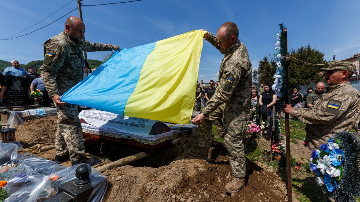 Varios militares sostienen una bandera ucraniana durante el entierro del soldado ucraniano Vasyl Pekar, de 37 años.