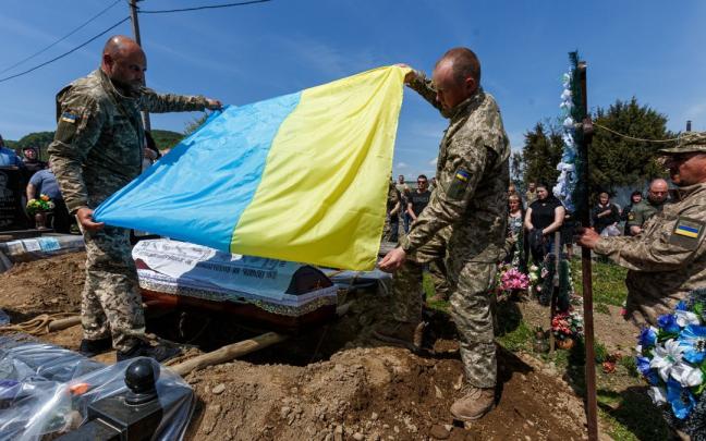 Varios militares sostienen una bandera ucraniana durante el entierro del soldado ucraniano Vasyl Pekar, de 37 años.