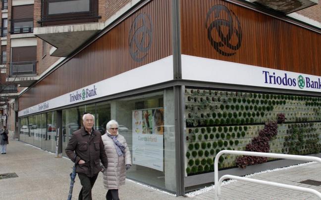 Dos personas pasan ante la entrada de la antigua oficina de Triodos Bank en Pamplona