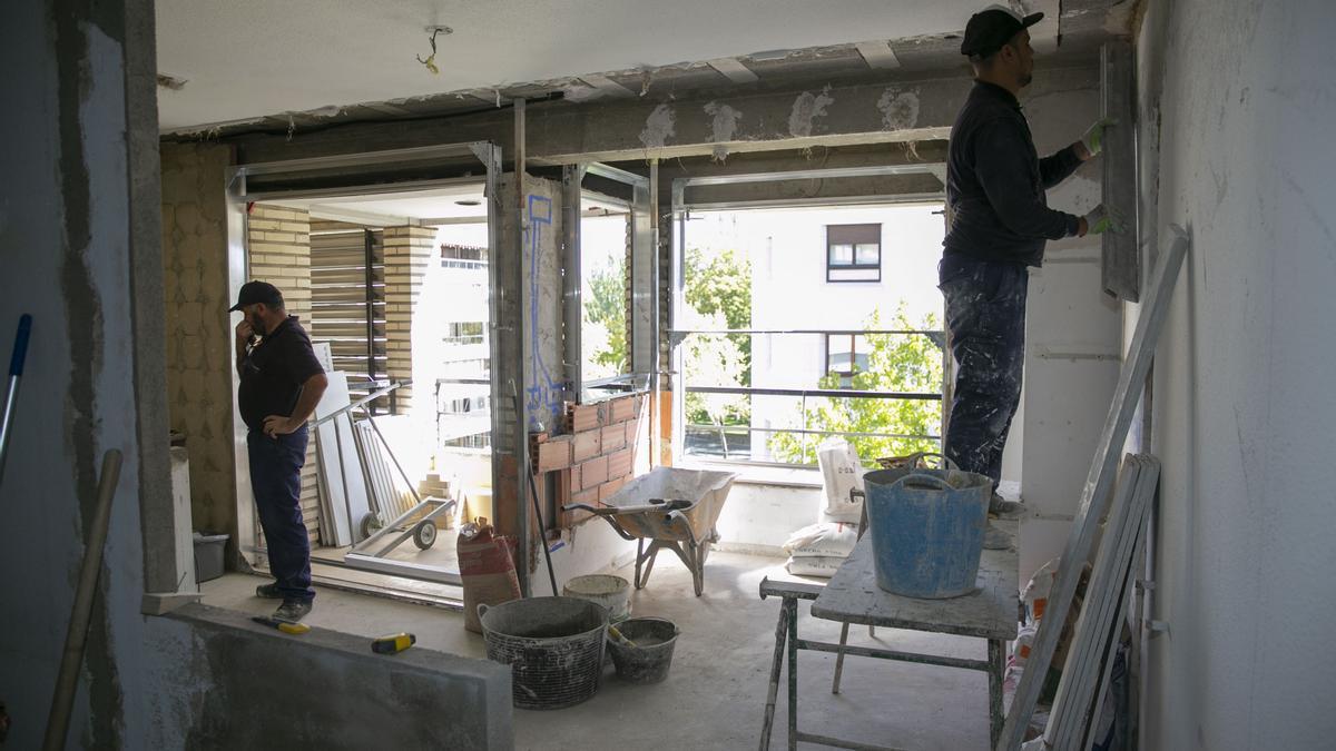 Dos albañiles trabajan en la rehabilitación de un apartamento.