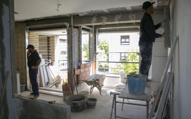 Dos albañiles trabajan en la rehabilitación de un apartamento.