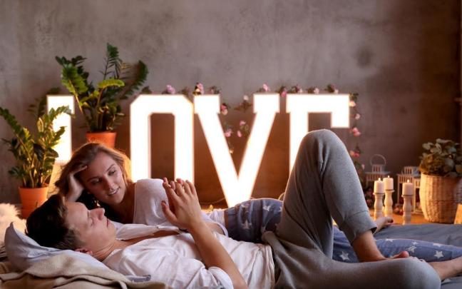 Una pareja tumbados sobre una cama en actitud cariñosa. Una pareja tumbados sobre una cama en actitud cariñosa.