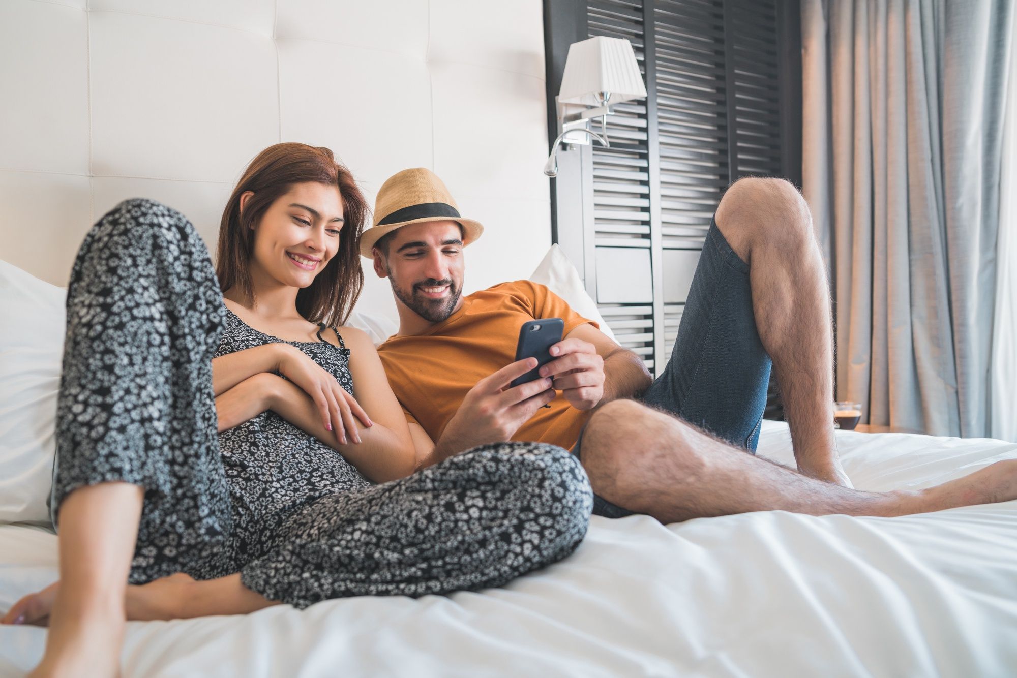 Una pareja acostada en la cama de un hotel.