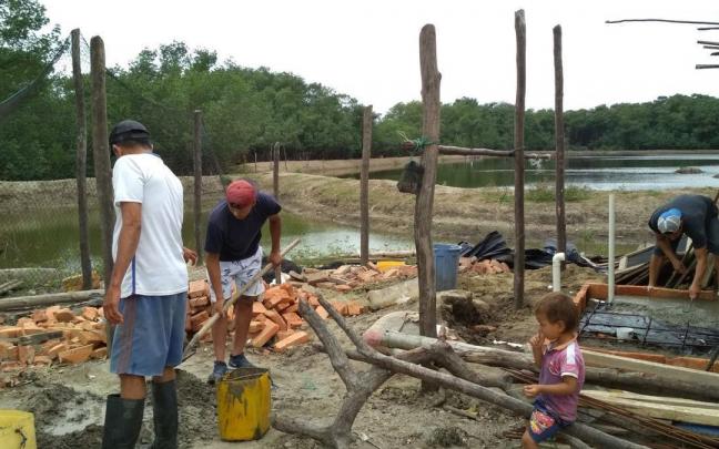 Dos habitantes de la comunidad de Colorado (Cojimíes) y un trabajador de Cáritas preparan cemento para construir un baño.