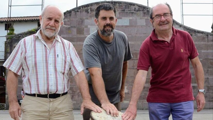 Txuma Prim, Pello Iriarte y Tiburcio Arraztoa posan con el botarri recuperado en la plaza de laxoa de Irurita.