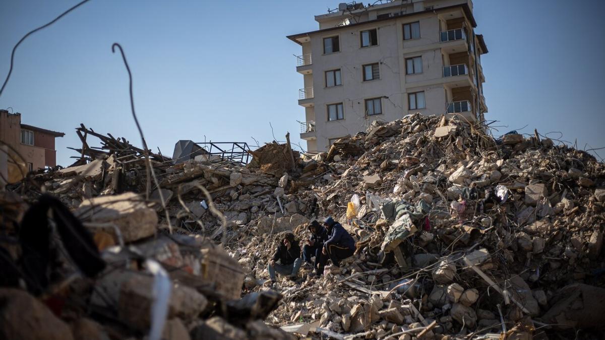 Tres hombres sentados entre las ruinas de un edificio en la ciudad turca de Hatay este martes, 14 de febrero