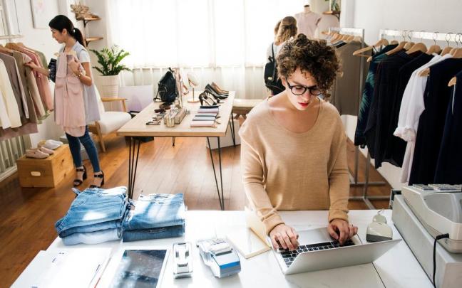Varias clientas miran ropa en un comercio.