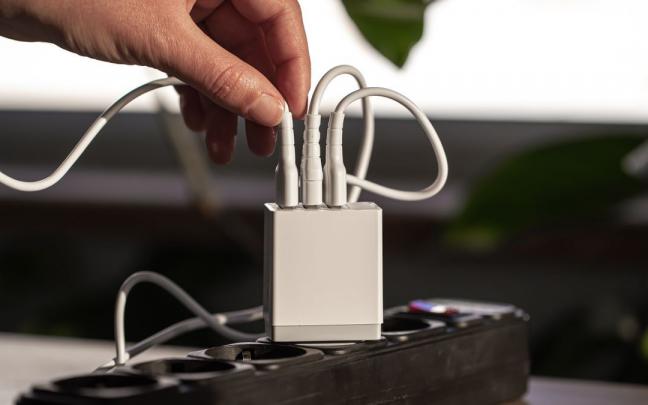 Una mujer desconecta uno de los cables USB de la regleta. Una mujer desconecta uno de los cables USB de la regleta.
