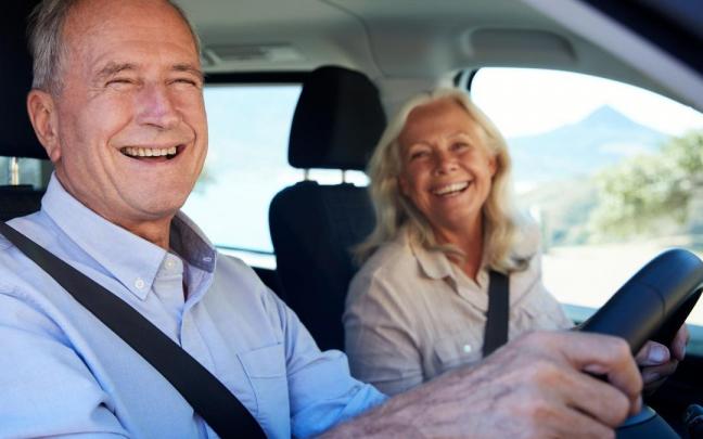 Un hombre mayor conduce un coche con su mujer de copiloto.