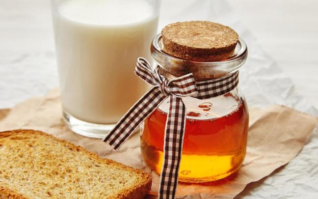 Un vaso de leche junto a un tarro de miel. Un vaso de leche junto a un tarro de miel.