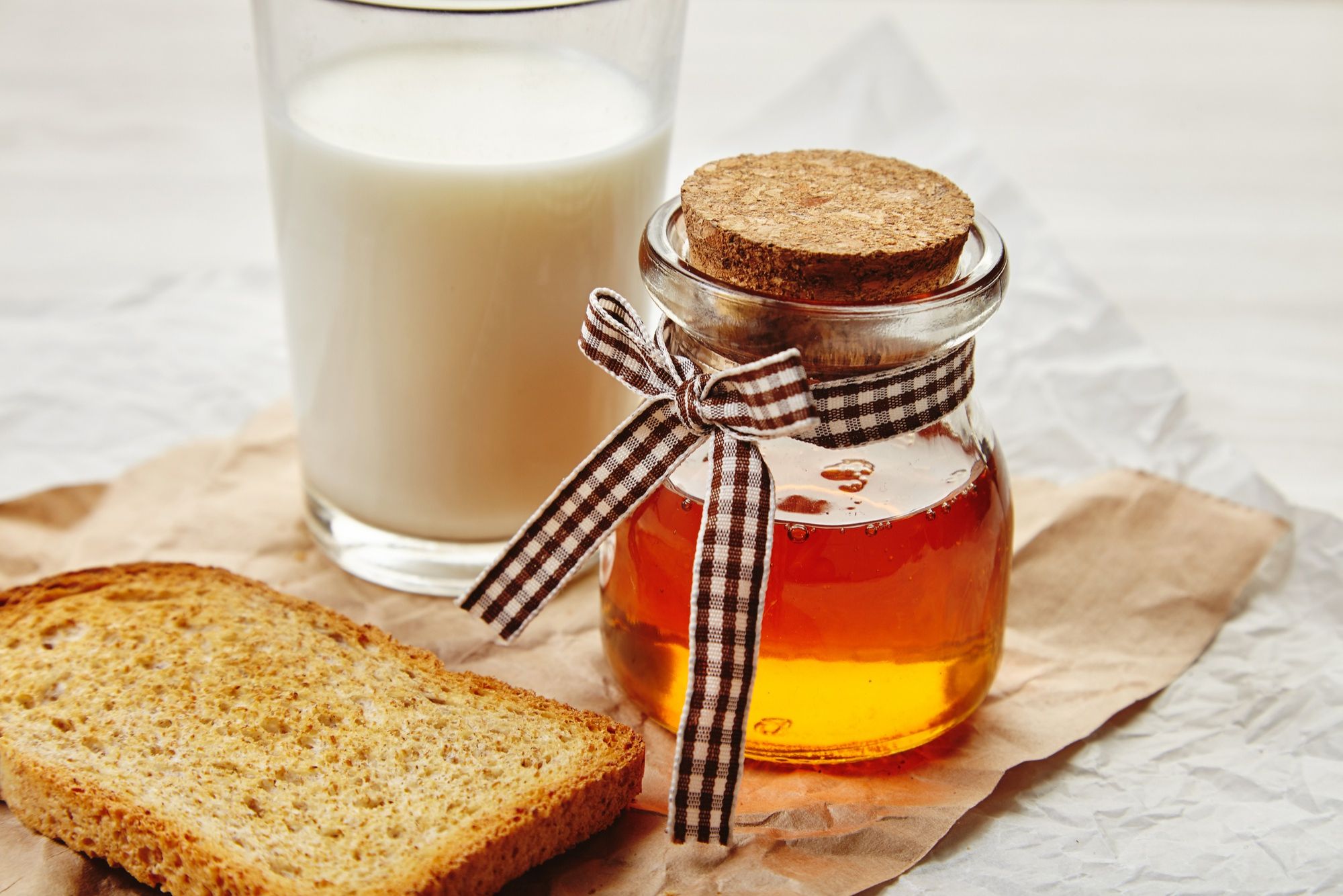 Un vaso de leche junto a un tarro de miel.