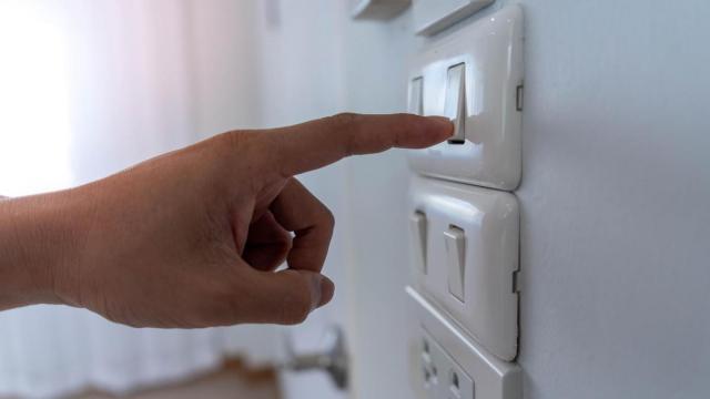Una persona enciende un interruptor de luz.