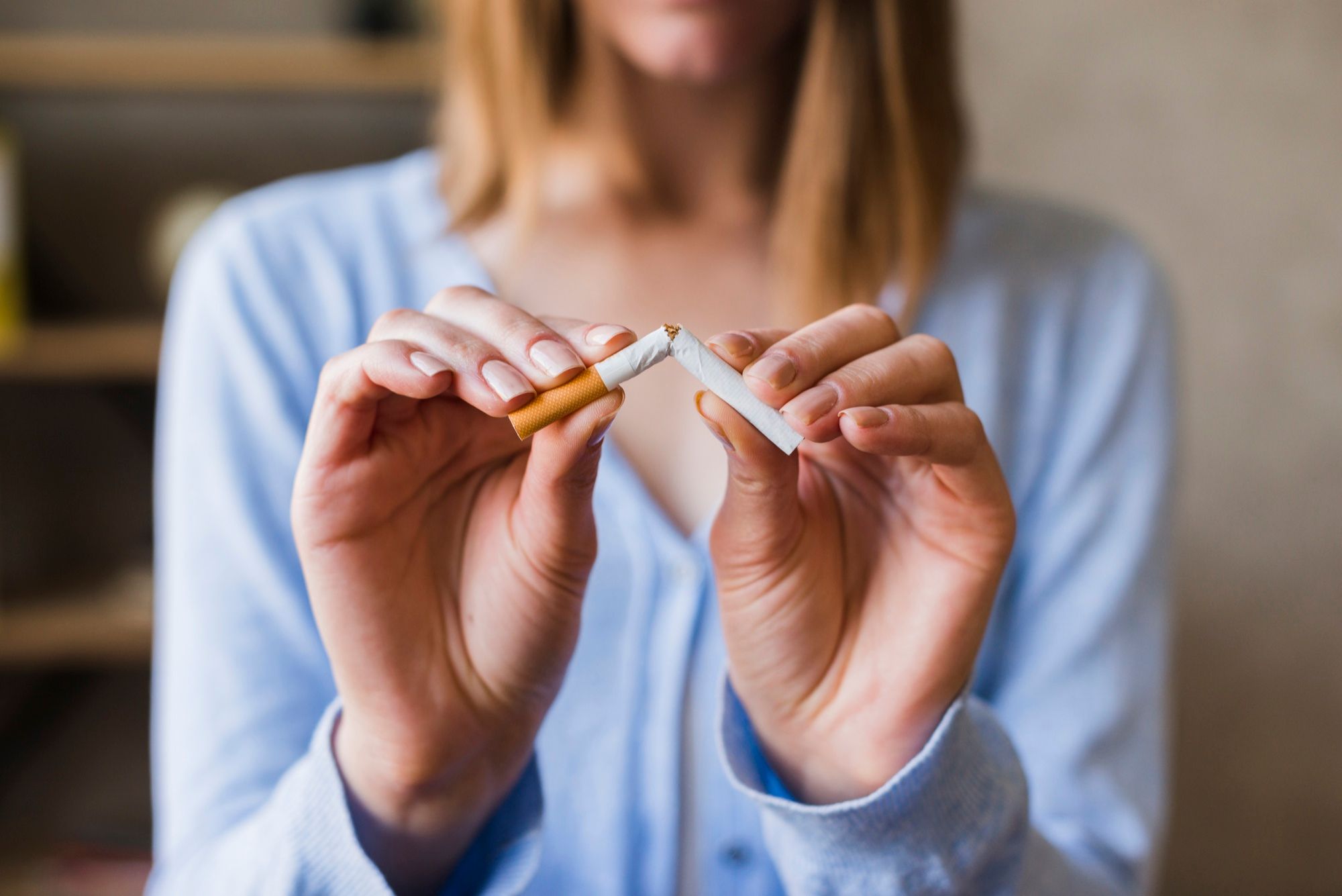 Una mujer parte un cigarrillo en dos.