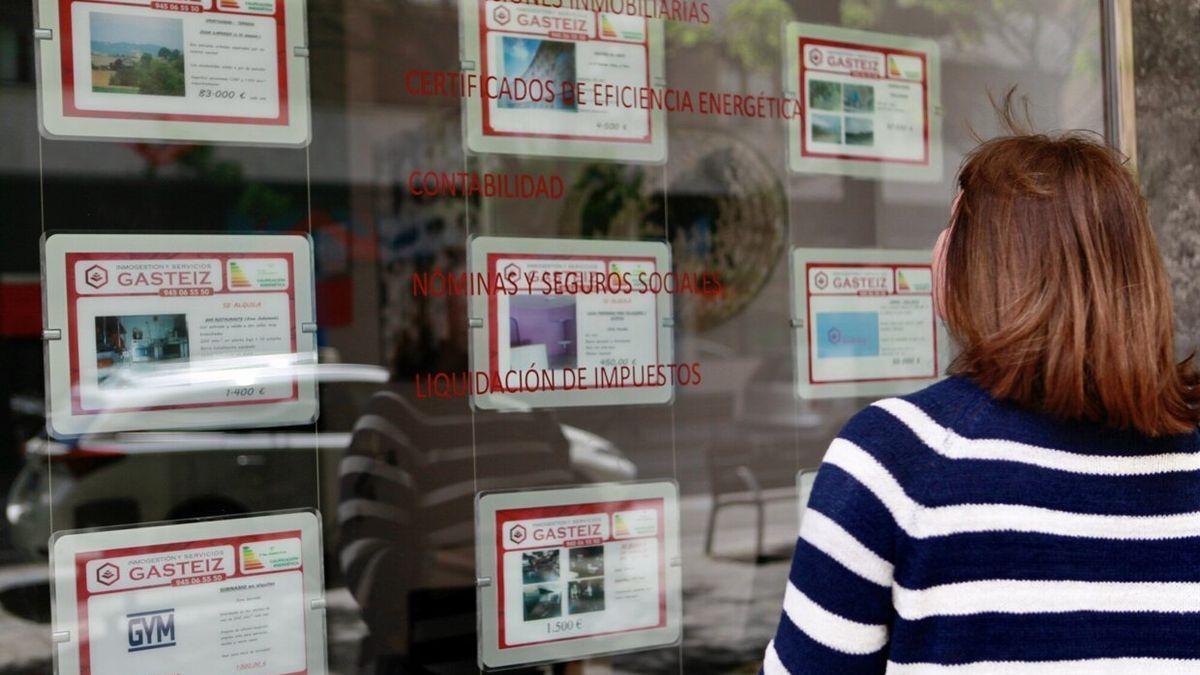 Una joven observa el escaparate e una inmobiliaria.