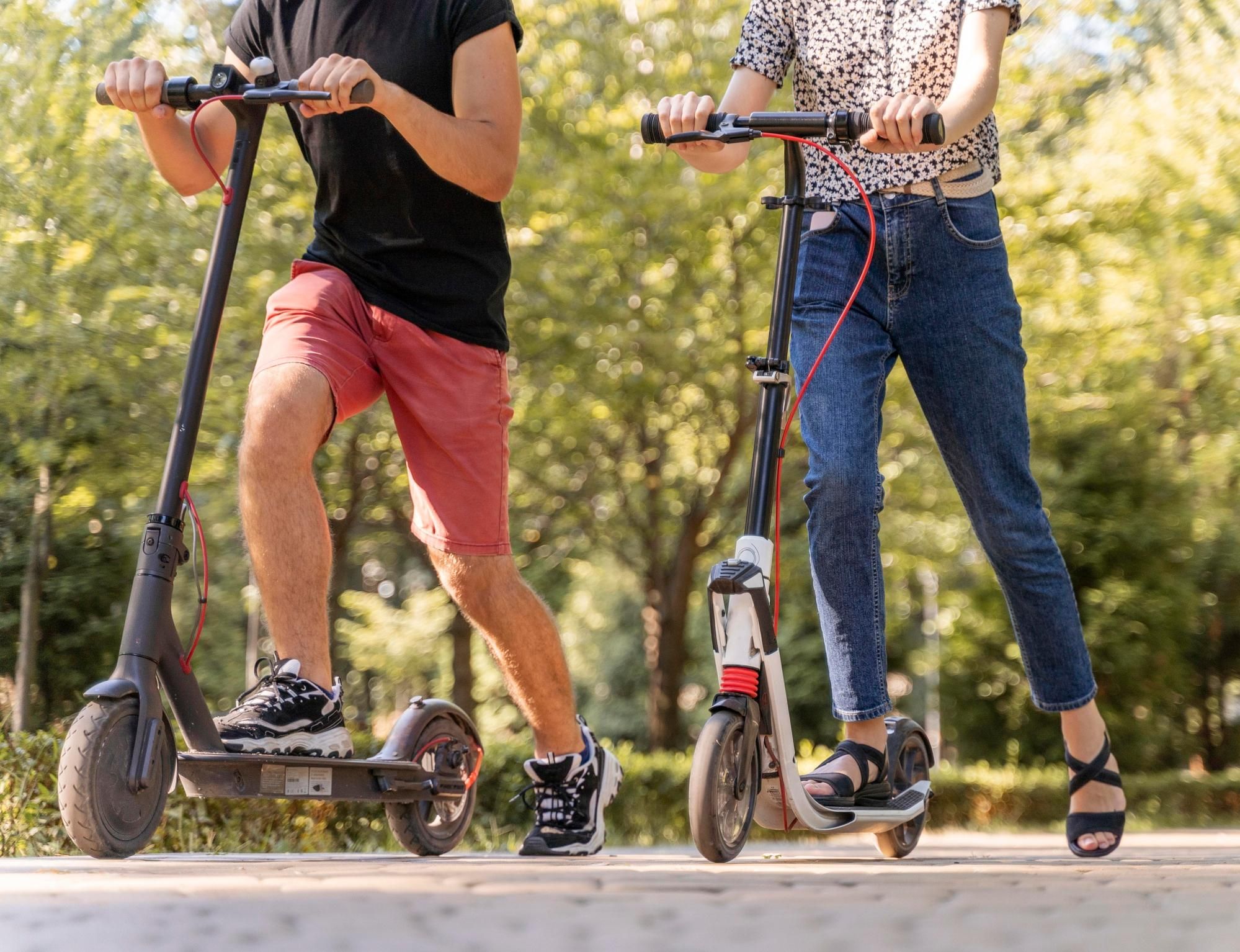 Un hombre y una mujer, circulando con sus patinetes eléctricos.